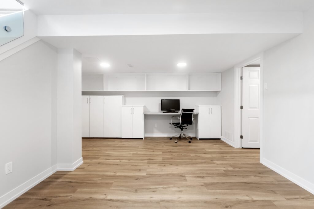 Basement renovation showcasing a modern workspace with white cabinetry and wooden flooring.