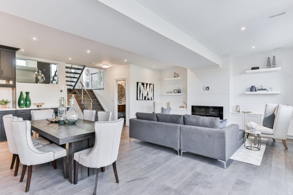 Spacious living and dining area showcasing a modern gut renovation with elegant furniture, floating shelves, and a contemporary staircase.