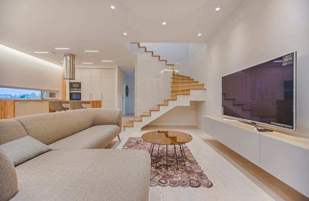 Modern living room designed by a Home Renovations Contractors Near Me, featuring a floating staircase, sleek kitchen appliances, and a spacious seating area.