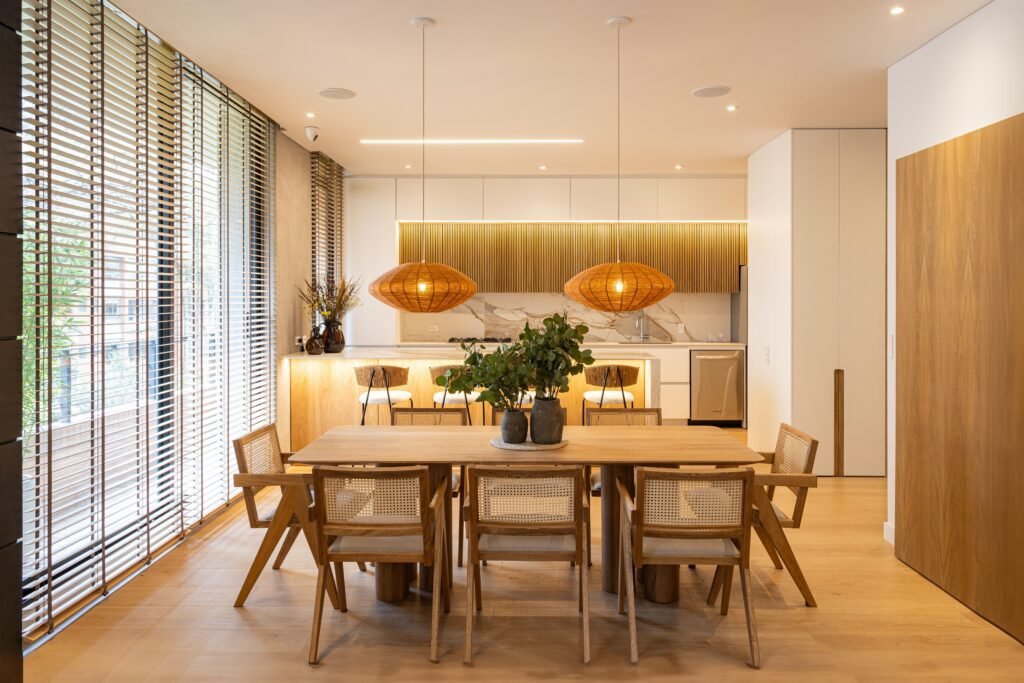 Modern dining and kitchen area designed by contractors for home remodeling, featuring wooden furniture and unique pendant lighting.