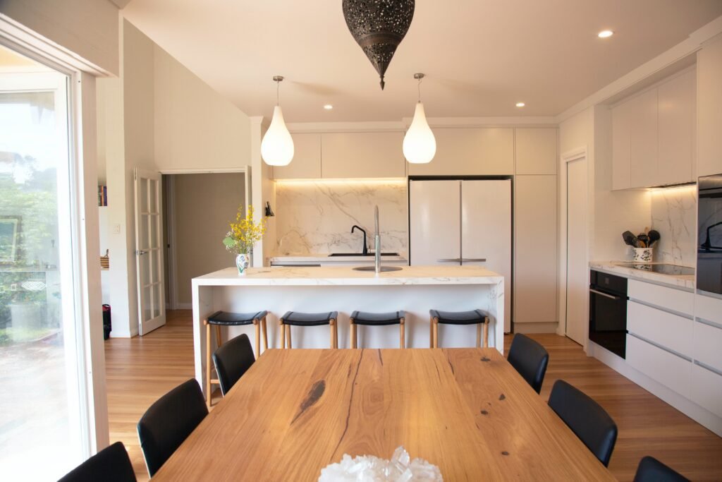 Modern kitchen remodeling showcasing Scandinavian style with sleek white cabinets, marble countertops, and pendant lighting.