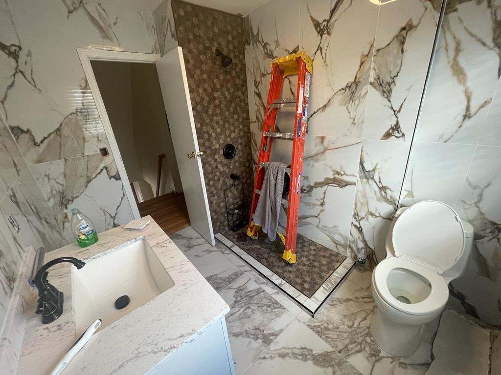 Modern bathroom renovation in Brooklyn NY mid-construction, featuring marble tiles, a white basin. Ongoing work